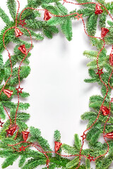 Naklejka na ściany i meble Christmas tree branches in the form of a frame, decorated with a red garland with bells and stars. flat lay, space for a text