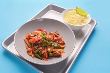 Fresh rice and chicken in gravy sauce with tomatoes, red pepper and green beans served in seperate plates on metal tray.