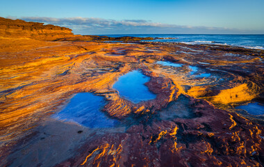 Fototapeta na wymiar Sunrise over the rocky coast with tide pools in Kalbarri National Park in West-Australia