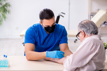 Fototapeta premium Old patient visiting young male doctor in blood transfusion conc