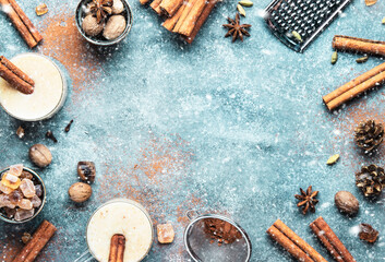 Eggnog hot winter or autumn cocktail drink with milk, eggs and dark rum, sprinkled with cinnamon and nutmeg in glass cups under the snow. Christmas table setting