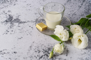 A cup of cold, fresh milk for breakfast. A bouquet of pink, white, purple eustoma for you, on a gray concrete table.