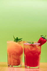Summer drinks with fruit juice and ice. Refreshing summer beverages in different glasses over green background.