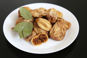 Dried figs in a white plate on a dark glass table