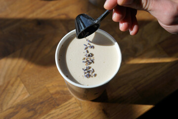 Barista prepares lavender creamy coffee in paper cup
