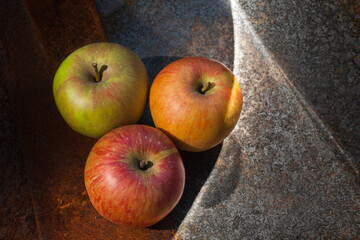 Zielone, czerwone i pomarańczowe jabłko na zardzewiałej blasze, aranżacja.
