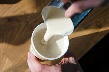 Barista prepares creamy coffee in paper cup