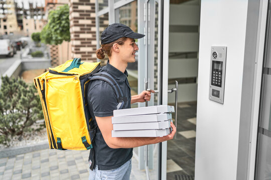 A man courier with a backpack and pizza delivered from restaurant an online order to the customer's home