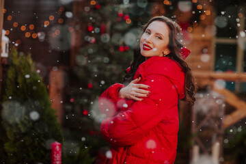 Young woman in red winter jacket posing under the snowing.