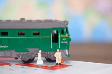 A doll model preparing to board the train next to the green leather train model