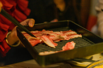 Hand using chopsticks pick raw sliced beef, vegetable, a piece of corn over the Chinese spicy hot pot, Szechuan Spicy Hot Pot
