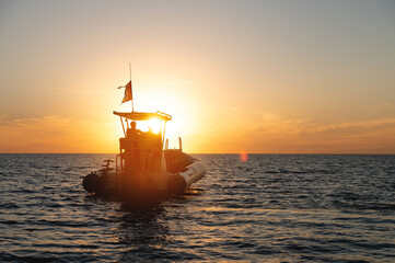 Tourist boat catamaran for hire of tourists with two sailors on board at sunset. Sea tourism on the...