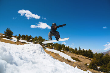 Stylish woman snowboarder makes a trick in flight. Snowboard jump from a kicker against the...
