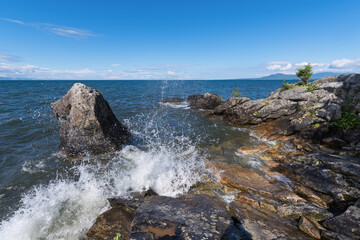 Obraz premium The foamy wave crashes on the rocky shore of Lake Baikal. Buryatia, Russia