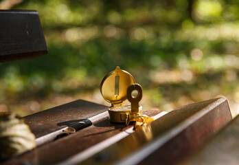 metal compass lies on a wooden bench in the park in the shade of trees. selective focus. background is blurred. High quality photo