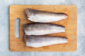 Raw hake fish carcass on a wooden chopping Board. top view Copy space