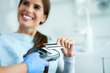 Adult woman paying for visit in dentist office