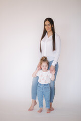 Little girl with mom in studio. White background