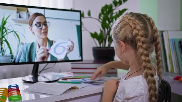 remote teaching, girl show cards with numbers during learning math to a female teacher from home with a computer