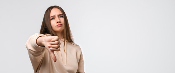 Young woman looking unhappy and angry showing dislike with thumb down, rejection concept. Copy space