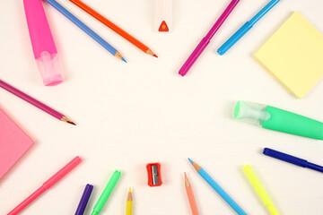 Flat lay. Colored pencils felt-tip pens pencil sharpener eraser on a white background. Frame.