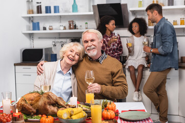 Selective focus of elderly man and woman with glasses of wine near food during thanksgiving celebration
