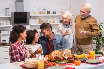 Selective focus of multicultural family celebrating thanksgiving near food on table