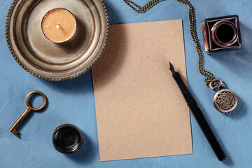 Brown kraft paper mockup with an ink pen and a vintage watch, shot from the top on a blue background
