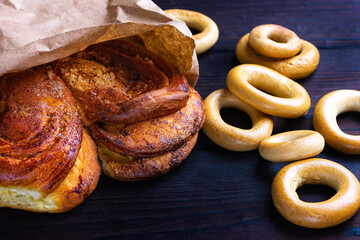 A bun, a bagel on a dark wooden background. Bakery counter