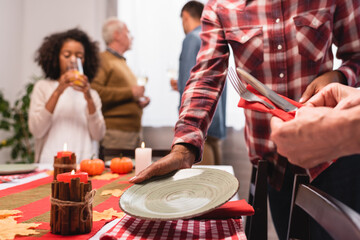 Selective focus of multiethnic women serving table during thanksgiving celebration