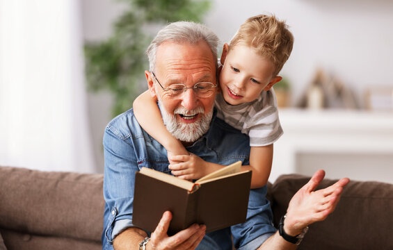 . Cheerful grandfather and grandson reading book together.