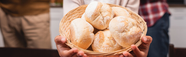 Panoramic crop of african american child holding basket with buns at home