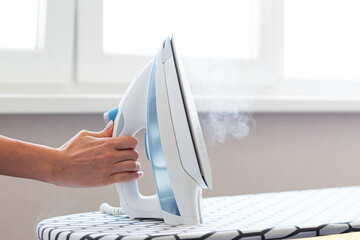Female hand ironing clothes on ironing board