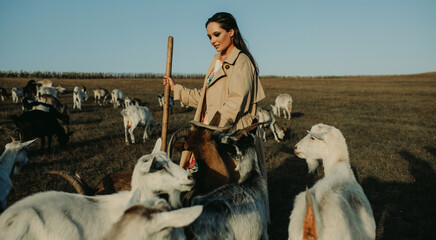 Shepherdess stands in a pasture among goats.