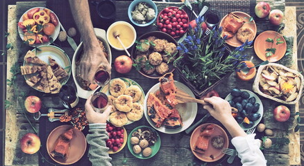 Country style. Thanksgiving table. A lot of food. The guests is hands hold wine over the set table. View from above.Art processing vintage