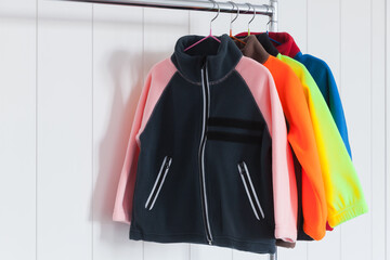 Colorful fleece jackets are hanging on hangers