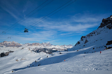 View of a ski resort piste with people skiing in Dolomites in Italy with cable car ski lift. Ski area Arabba. Arabba, Italy - obrazy, fototapety, plakaty