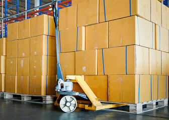 Cargo shipment, Commercial warehousing. Stack of cartons product boxes and hand pallet truck at the warehouse storage.