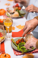 Cropped view of senior man eating lettuce near wife and thanksgiving dinner