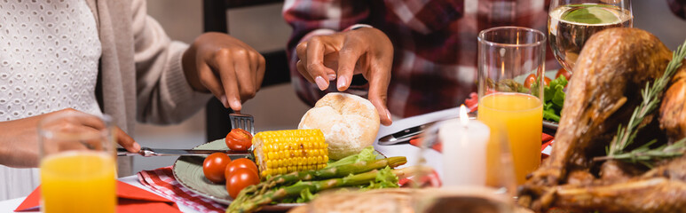Horizontal image of african american mother and daughter sitting near tasty food during thanksgiving celebration