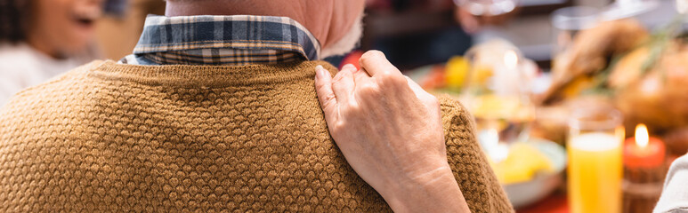 Panoramic shot of senior woman hugging husband during thanksgiving celebration with family