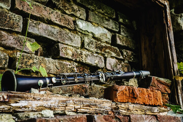 Old dirty clarinet on a background of a beautiful old broken brick wall. Selective focus on...