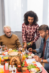 african american woman serving food on plate of man on thanksgiving