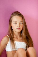 portrait of a gentle 9-year-old long-haired girl in a light T-shirt against a lilac wall