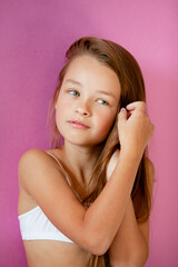 portrait of a gentle 9-year-old long-haired girl in a light T-shirt against a lilac wall