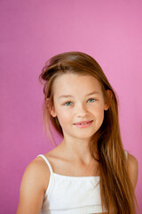 portrait of a gentle 9-year-old long-haired girl in a light T-shirt against a lilac wall