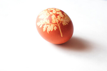 Painted Easter egg on a white background. Floral pattern on a red eggshell. Festive food.