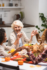 selective focus of senior woman looking at african american girl while holding hands on thanksgiving