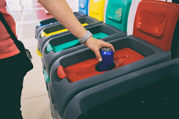 The woman throws the aluminum can into one from four bins for sorting garbage