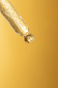 macro of pipette with liquid and drop on gold background